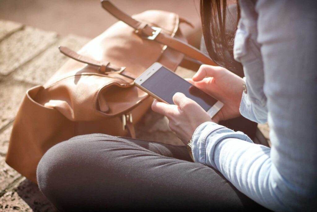 Mujer con mochila se sienta y escribe en su teléfono