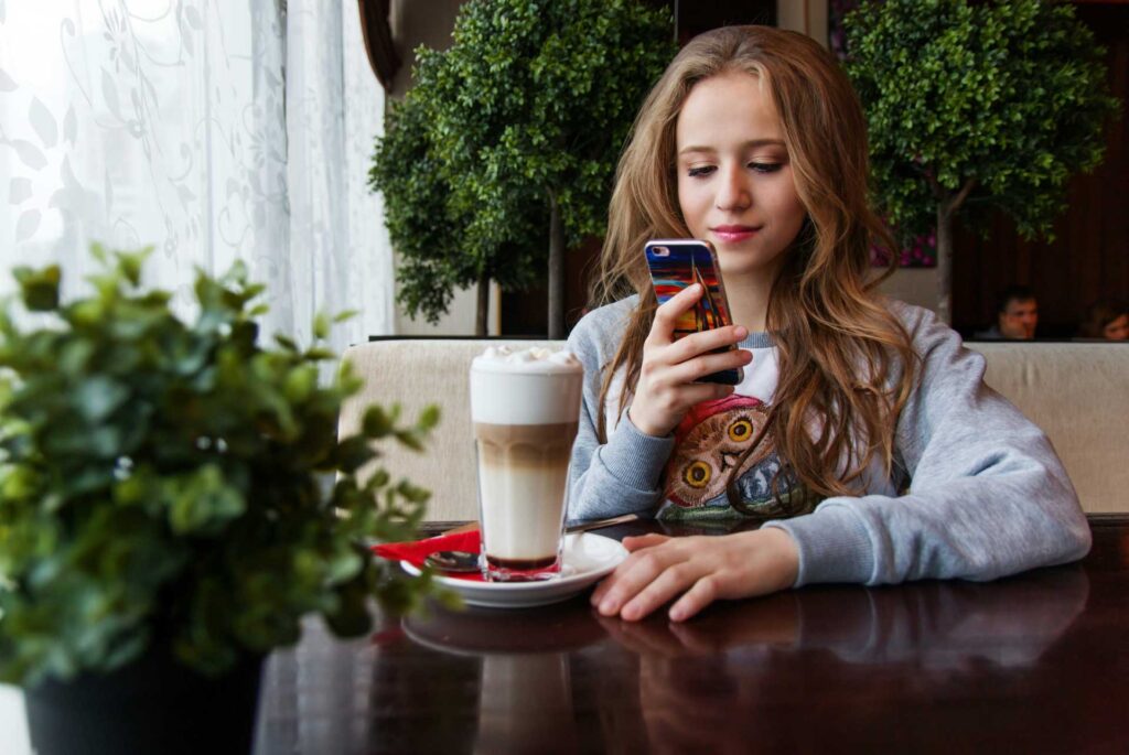 Chica en café viendo su celular