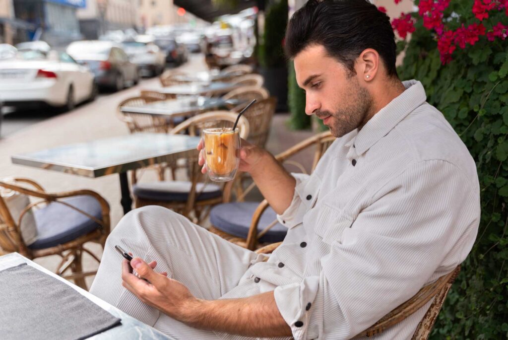 Hombre sentado en un café revisando su celular