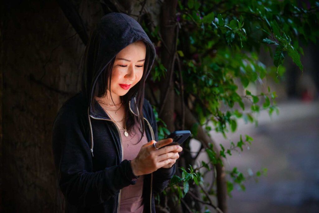 Mujer con sudadera y gorro mira su celular fijamente