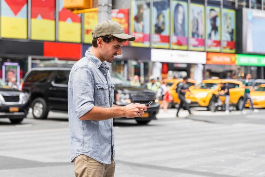 Un chico caminando por las calles enviando un mensaje de texto