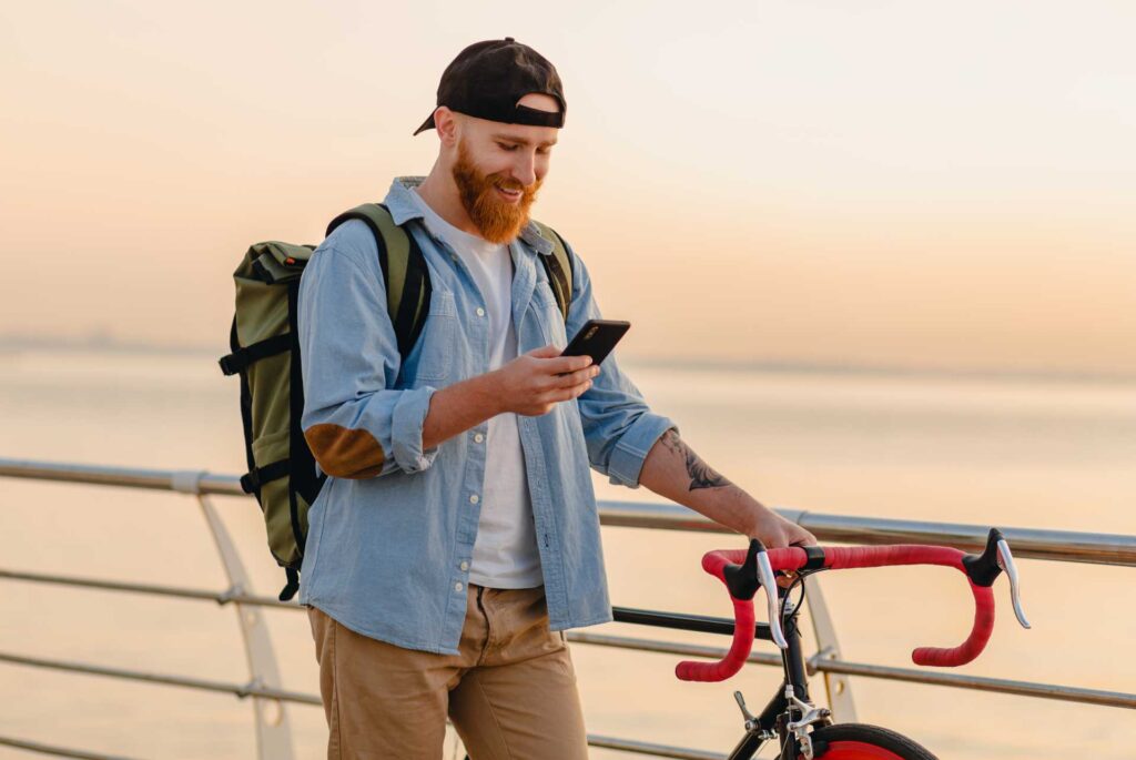 Hombre sosteniendo una bicicelta y con su teléfono en mano