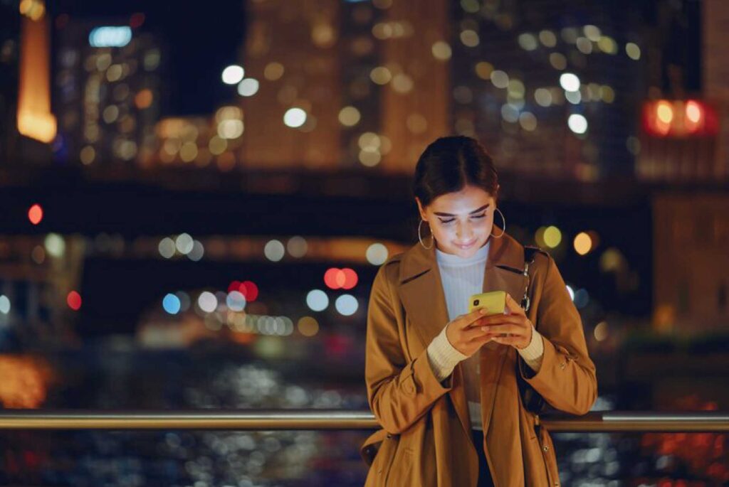 Chica texteando en la noche en las calles de Chicago