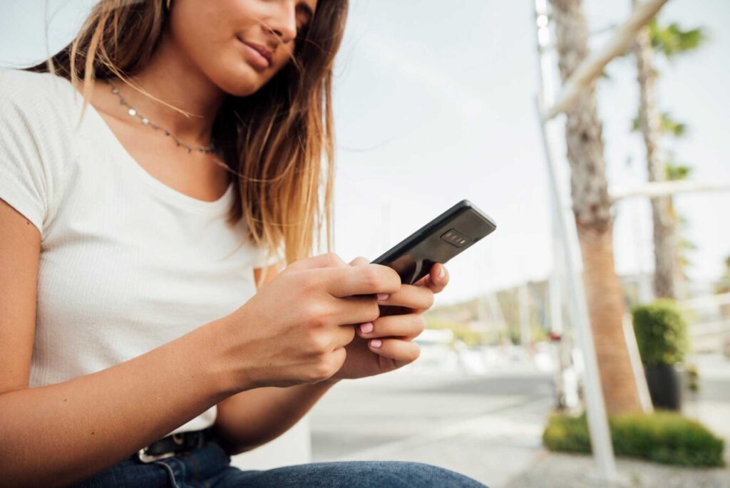 Joven sentada en la calle enviando mensaje