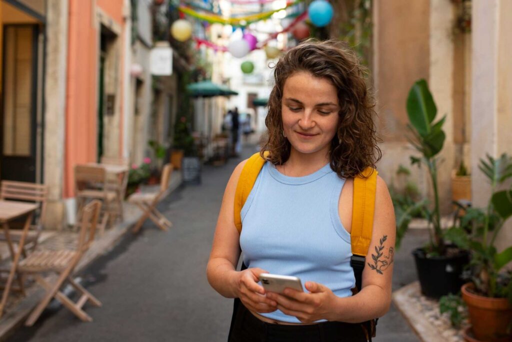 Mujer con celular en mano enviando mensaje en un pueblito de México