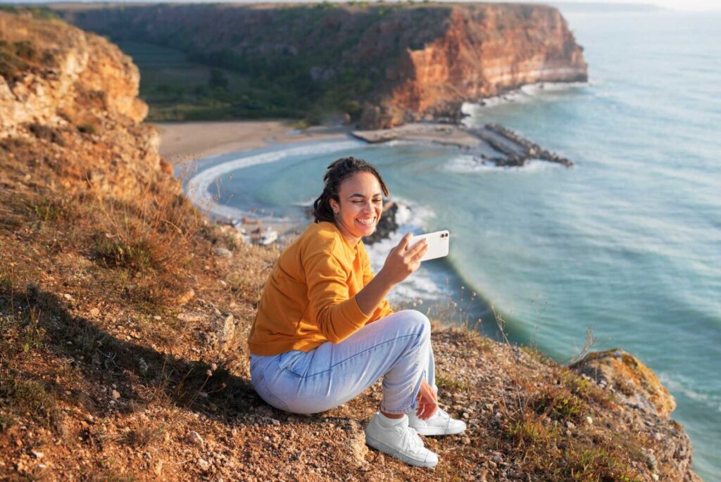 Mujer sentada en la orilla del mar se toma una selfie